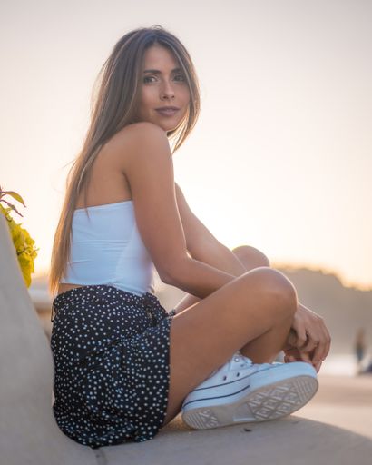 A vertical shot of an attractive female sitting on stairs by the beach captured in Zarautz, Spain