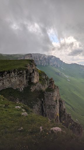 Dramatic mountain landscape with rugged cliffs and overcast sky, showcasing natural beauty and rugged terrain.