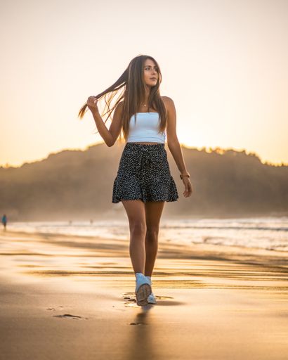A vertical shot of an attractive brunette walking on a beach in Zarautz, Spain