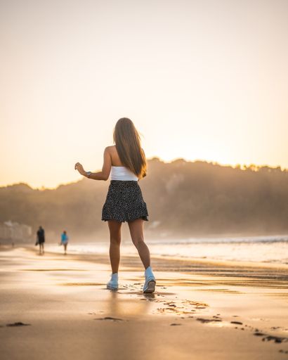A vertical shot of an attractive brunette woman in the sandy beach in Zarautz, Spain
