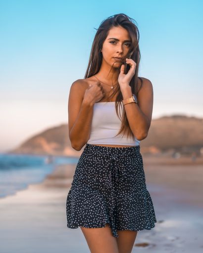 A vertical shot of a beautiful young female in casual summer clothing posing while walking in the beach of Zarautz, Spain