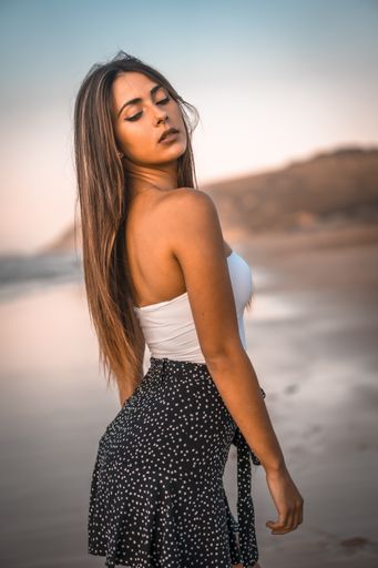 A vertical shot of an attractive brunette posing at the beach in Zarautz, Spain
