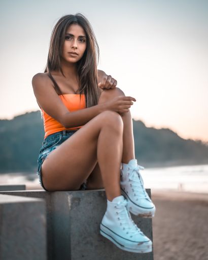 A vertical shot of an attractive female sitting on the beach by the ocean captured in Zarautz, Spain