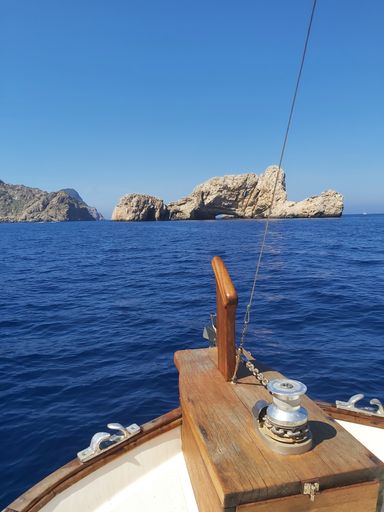 A serene view of a cliff by the ocean seen from a ship in daylight