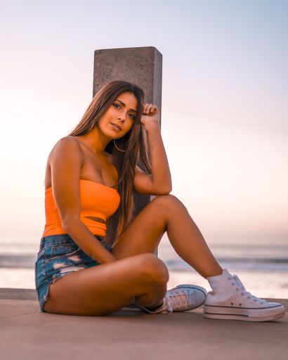 A vertical shot of an attractive female sitting on the beach by the ocean captured in Zarautz, Spain