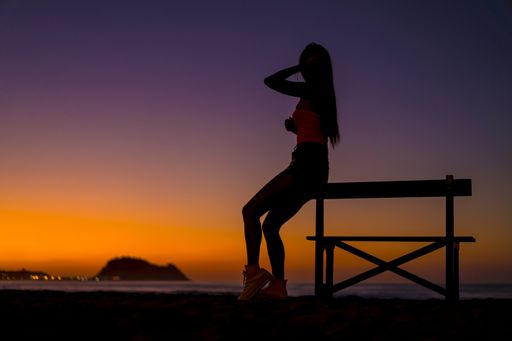 The silhouette of a female by a bench on the beach captured at sunset in Zarautz, Spain