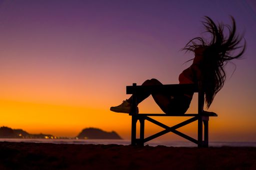 The silhouette of a female with her hair in the wind on the beach captured at sunset in Zarautz, Spain