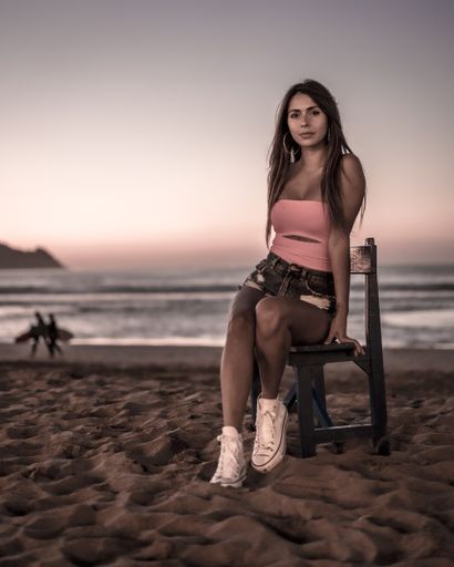 A vertical shot of an attractive female sitting on a bench on the beach captured in Zarautz, Spain
