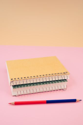 A vertical shot of closed notebook on a pink background with copy space