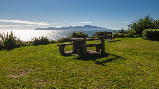 A picnic table with Tasman Sea view and Kapiti Island in autumn sun