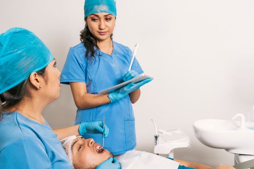 A female dentist and nurse working on a patient's mouth with electric tools in a dental clinic