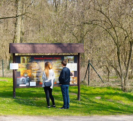 A back view of a young couple reading the information sign about Fort III and Nowe zoo in Poznan