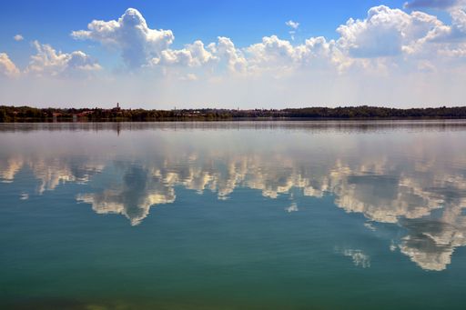 A serene landscape of the clouds reflecting on the clear water of the lake in daylight