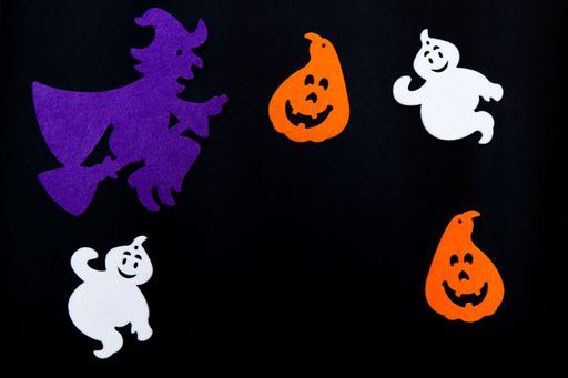 Black background with figures of ghosts, pumpkins and Halloween witches, with copy space