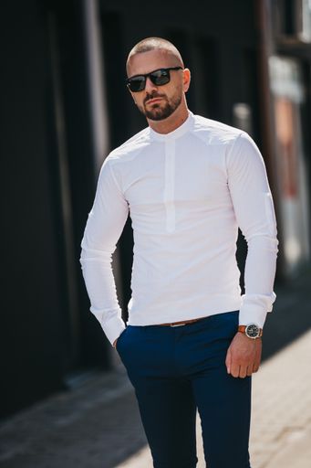 A cool handsome Caucasian man wearing an elegant white shirt and sunglasses posing outdoor