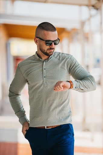 A cool handsome Caucasian man wearing an elegant gray shirt and sunglasses posing outdoor