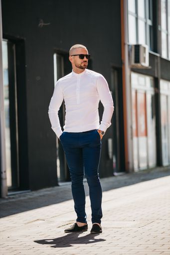 A cool handsome Caucasian man wearing an elegant white shirt and sunglasses posing outdoor
