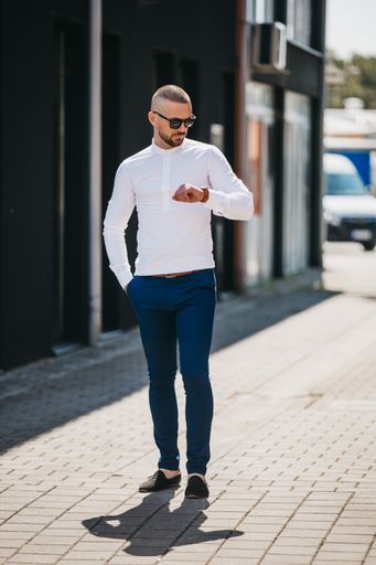 A cool handsome Caucasian man wearing an elegant white shirt and sunglasses posing outdoor