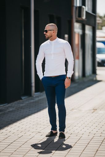 A cool handsome Caucasian man wearing an elegant white shirt and sunglasses posing outdoor