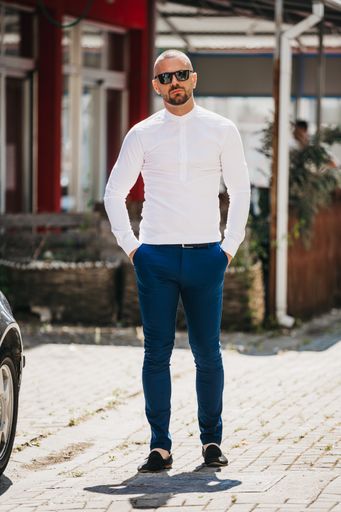 A cool handsome Caucasian man wearing an elegant white shirt and sunglasses posing outdoor