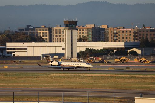 A Gulfstream G650ER arriving at San Jose international airport with control tower and Santa Cruz mountains in the background