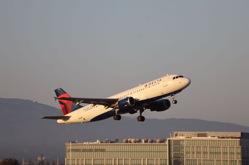 A Delta Airlines Airbus A320 taking off from San Jose international airport with Santa Cruz mountains in the background.