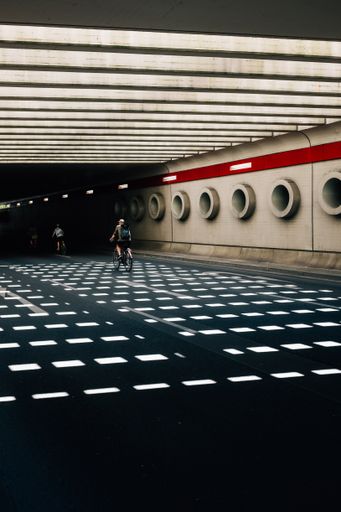 A vertical shot of people cycling through a tunnel with geometric architecture