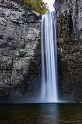 A vertical shot of the cliffs with a waterfall on a sunny day