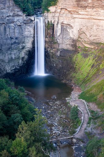 A vertical shot of the cliffs with a waterfall on a sunny day