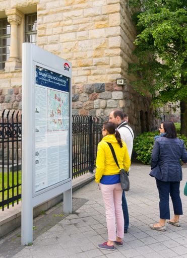 A couple and a female standing in front of a city map on a sunny day