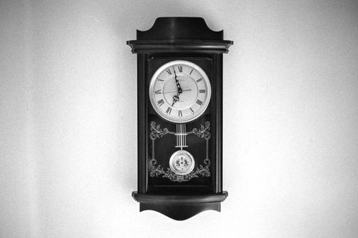 A monochrome shot of an antique wooden wall clock
