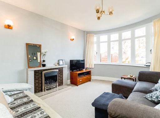 A bright living room with a cozy fireplace, modern furniture, and large windows allowing natural light.