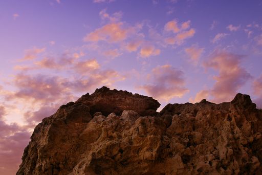 The rocky cliffs of Algarve under pink dreamy fluffy clouds during the sunset in Albufeira, Portugal