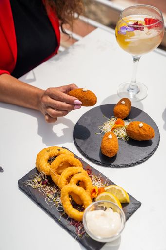 Delicious croquettes and calamari rings with sauce and a refreshing cocktail served al fresco.