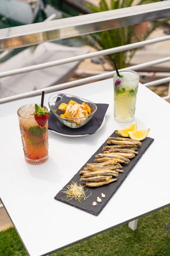 Spanish tapas, including fried fish and patatas bravas, along with refreshing cocktails in an open-air restaurant overlooking a marina.