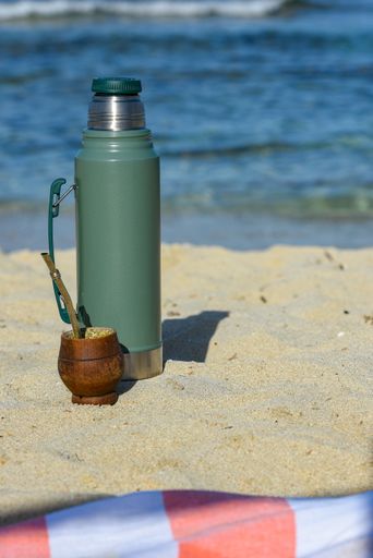 A vertical shot of a Stanley thermos on the beach