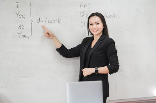 A female teacher in a black business suit and with a laptop in a classroom