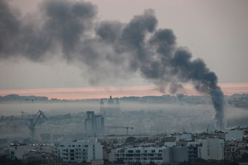 Smog from factories and vehicular traffic occupying lower lying areas of southern Malta, with black sooty smoke from burning rubber.