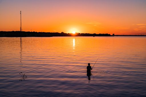 A silhouette of a man fishing at sunset at Lake Tawakoni State Park, Texas