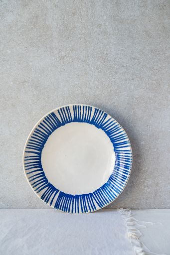 A white ceramic plate with blue stripes is displayed against a textured background.