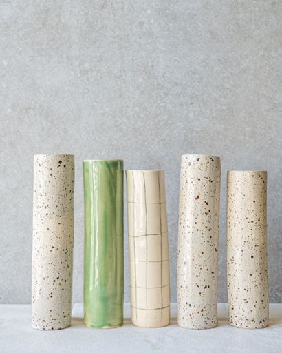 Five tall, cylindrical vases standing against a neutral background.