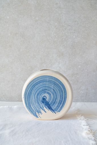 A white ceramic vase with a blue swirl design.