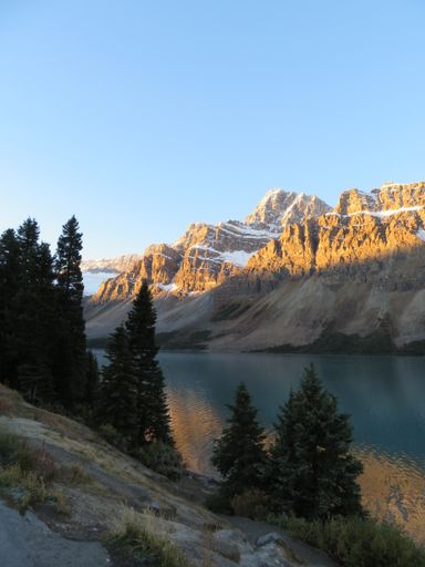 A vertical shot of high mountains and their reflection in a lake on a sunny day in Canada