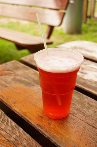 A vertical closeup shot of a cup of cold beer with a straw