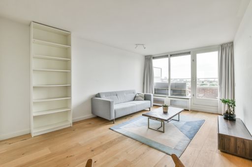 An interior shot of a living room with some furniture with white walls and wooded floor