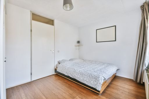 An interior shot of a bedroom in white walls and a wooden floor