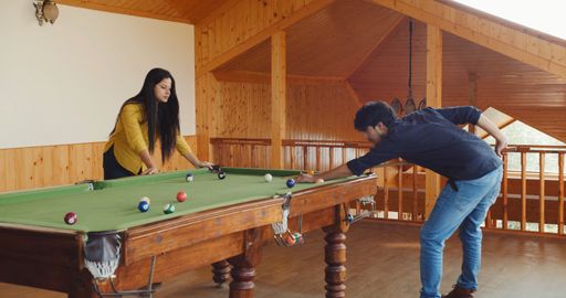 A young Indian guy is hitting a ball on the pool table