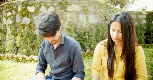 A South Asian couple from India sitting on outside grass