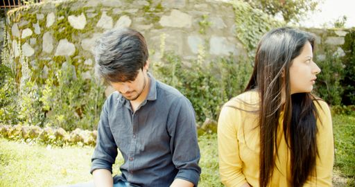 A South Asian couple from India sitting on outside grass