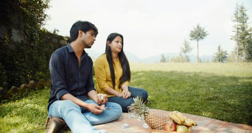 A South Asian couple from India sitting on outside grass